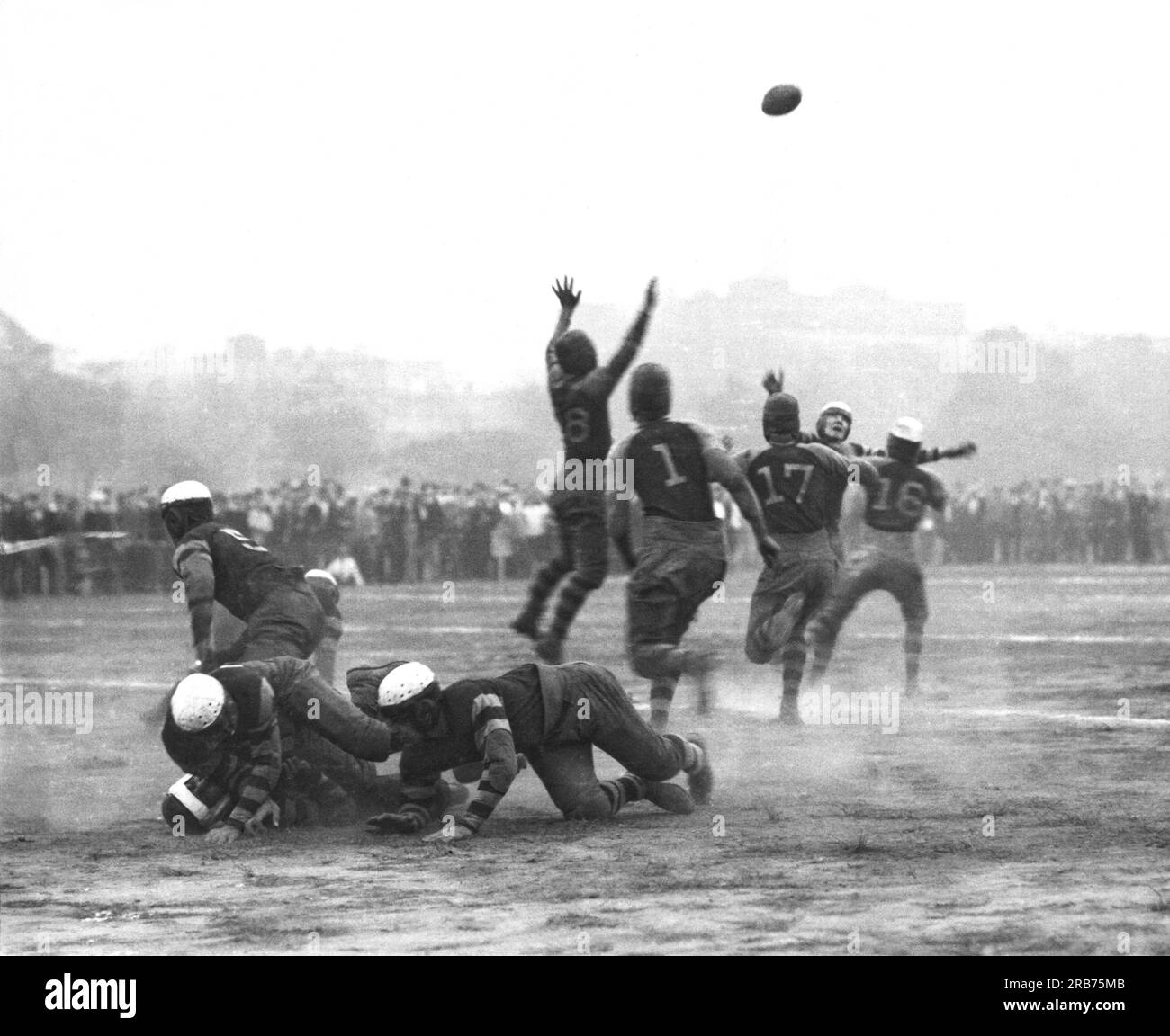 United States:  c. 1920 A quarterback throws the football just as he is being rushed by four other players. Stock Photo