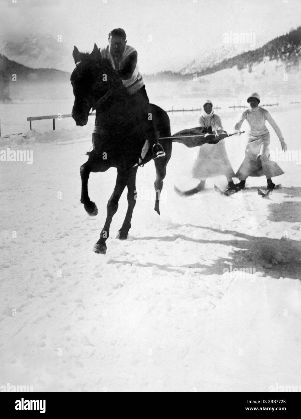 Jena, Germany: c. 1895. Two skiers enjoying the sport of skijoring behind a horse on a snow covered road in Germany. Stock Photo