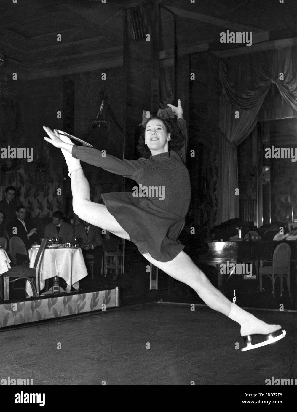New York, New York:  c. 1940  A new trend in night club entertainment: ice skating!  This girl is showing how skillful she is to an admiring audience. Stock Photo