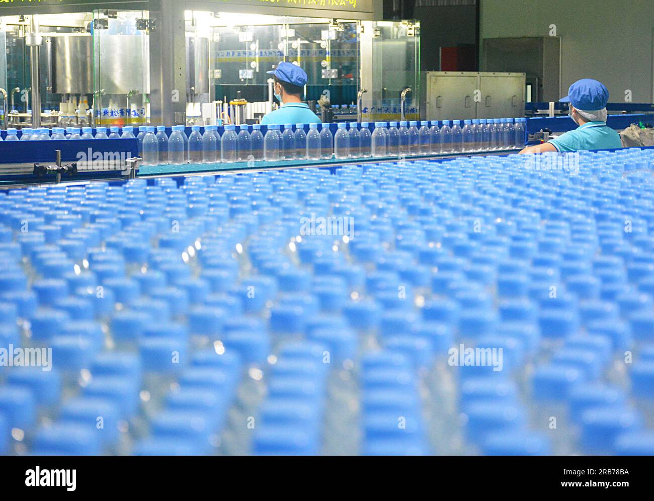 ANQING, CHINA - JULY 8, 2023 - Workers rush to make bottled water at the production workshop of a beverage company in the Economic development zone of Stock Photo