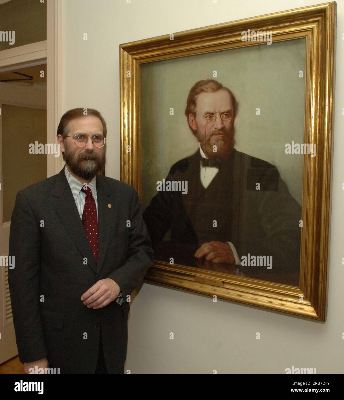 Office of Budget Director John Trezise, posing next to painted portrait of former Secretary of the Interior (1877-1881) Carl Schurz Stock Photo