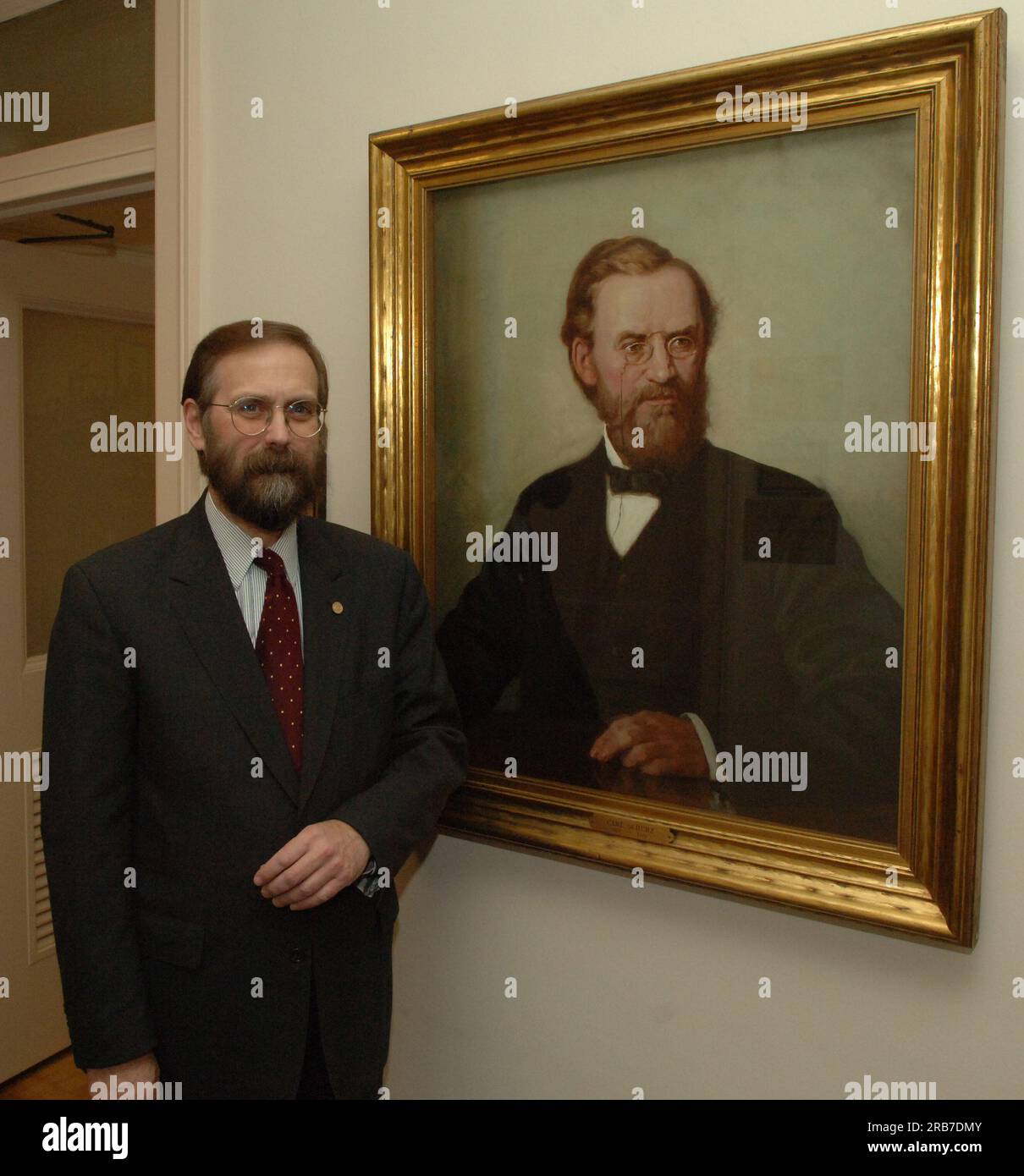 Office of Budget Director John Trezise, posing next to painted portrait of former Secretary of the Interior (1877-1881) Carl Schurz Stock Photo