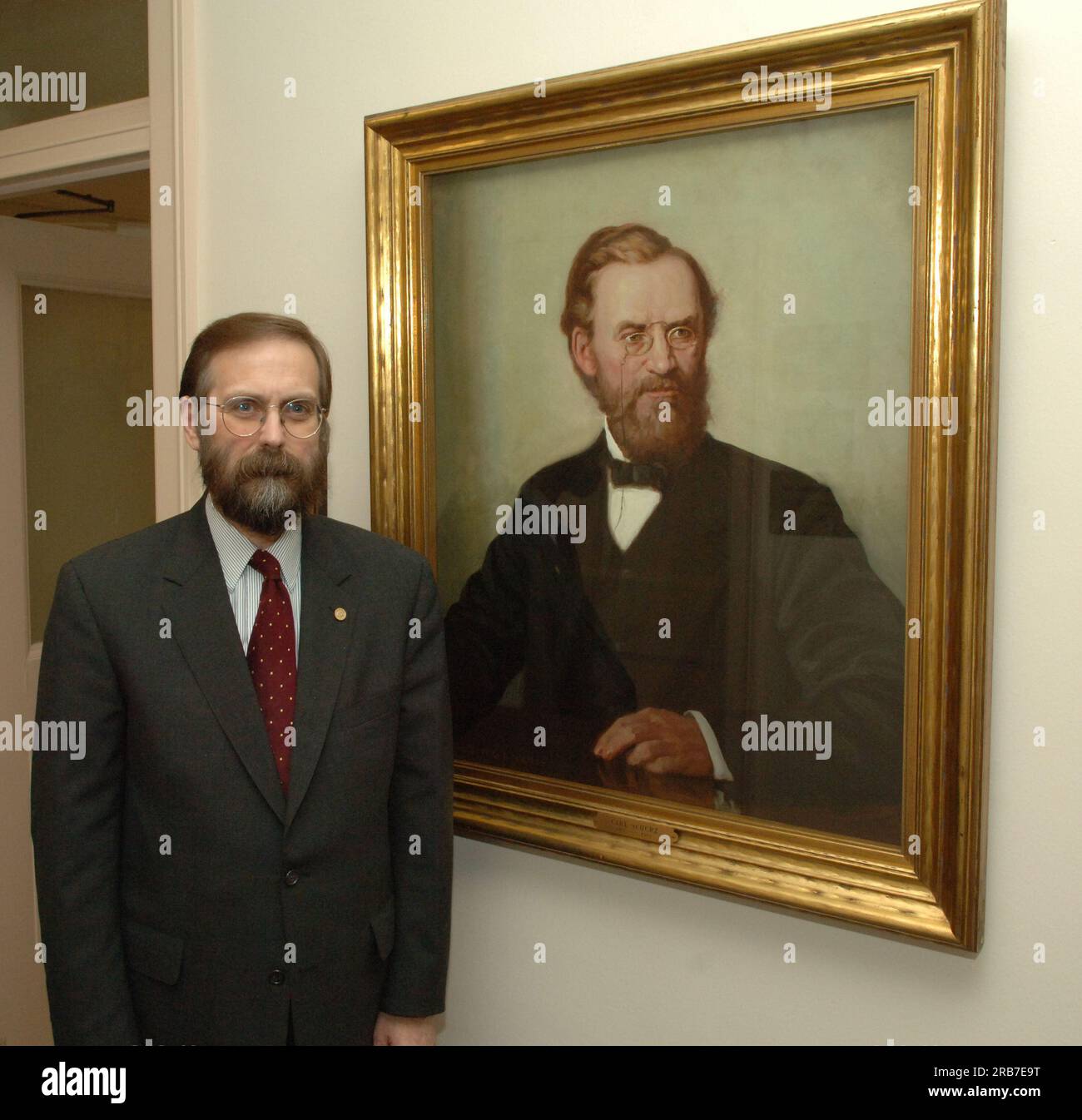 Office of Budget Director John Trezise, posing next to painted portrait of former Secretary of the Interior (1877-1881) Carl Schurz Stock Photo