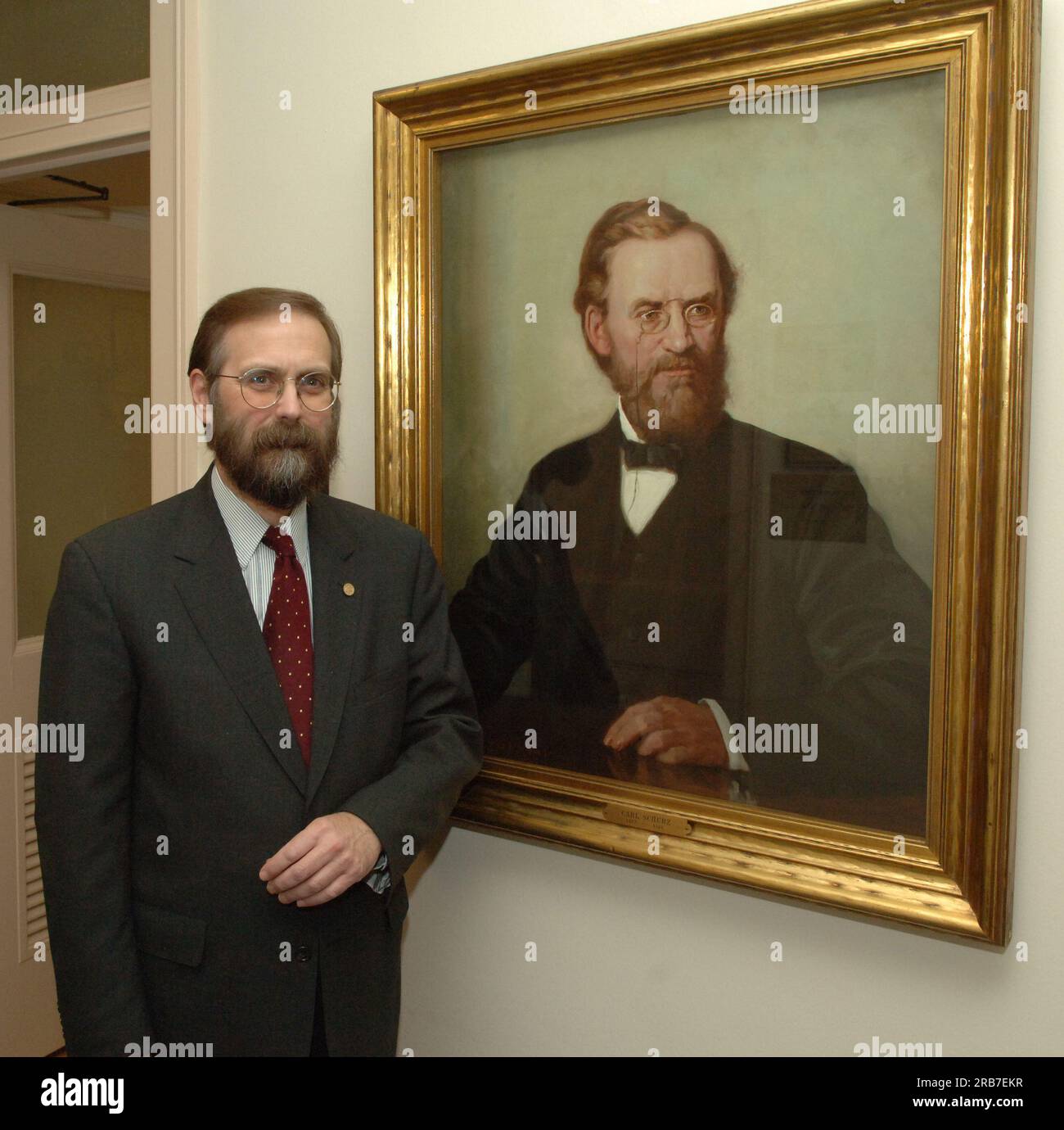 Office of Budget Director John Trezise, posing next to painted portrait of former Secretary of the Interior (1877-1881) Carl Schurz Stock Photo