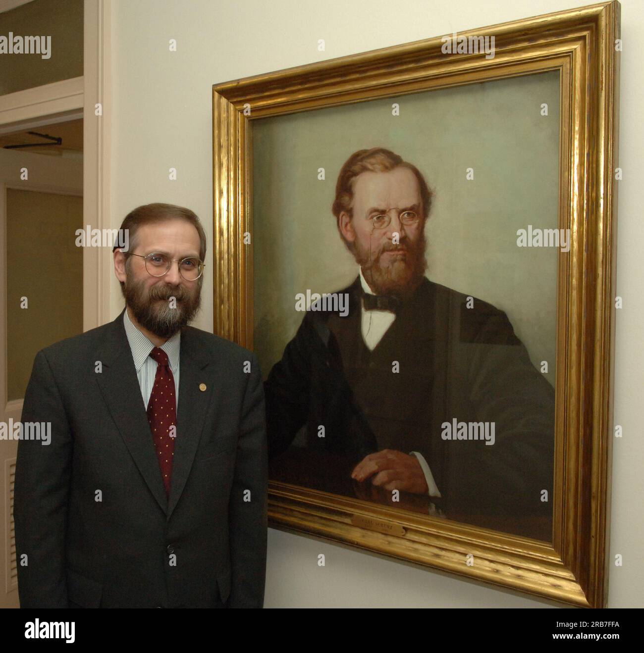 Office of Budget Director John Trezise, posing next to painted portrait of former Secretary of the Interior (1877-1881) Carl Schurz Stock Photo