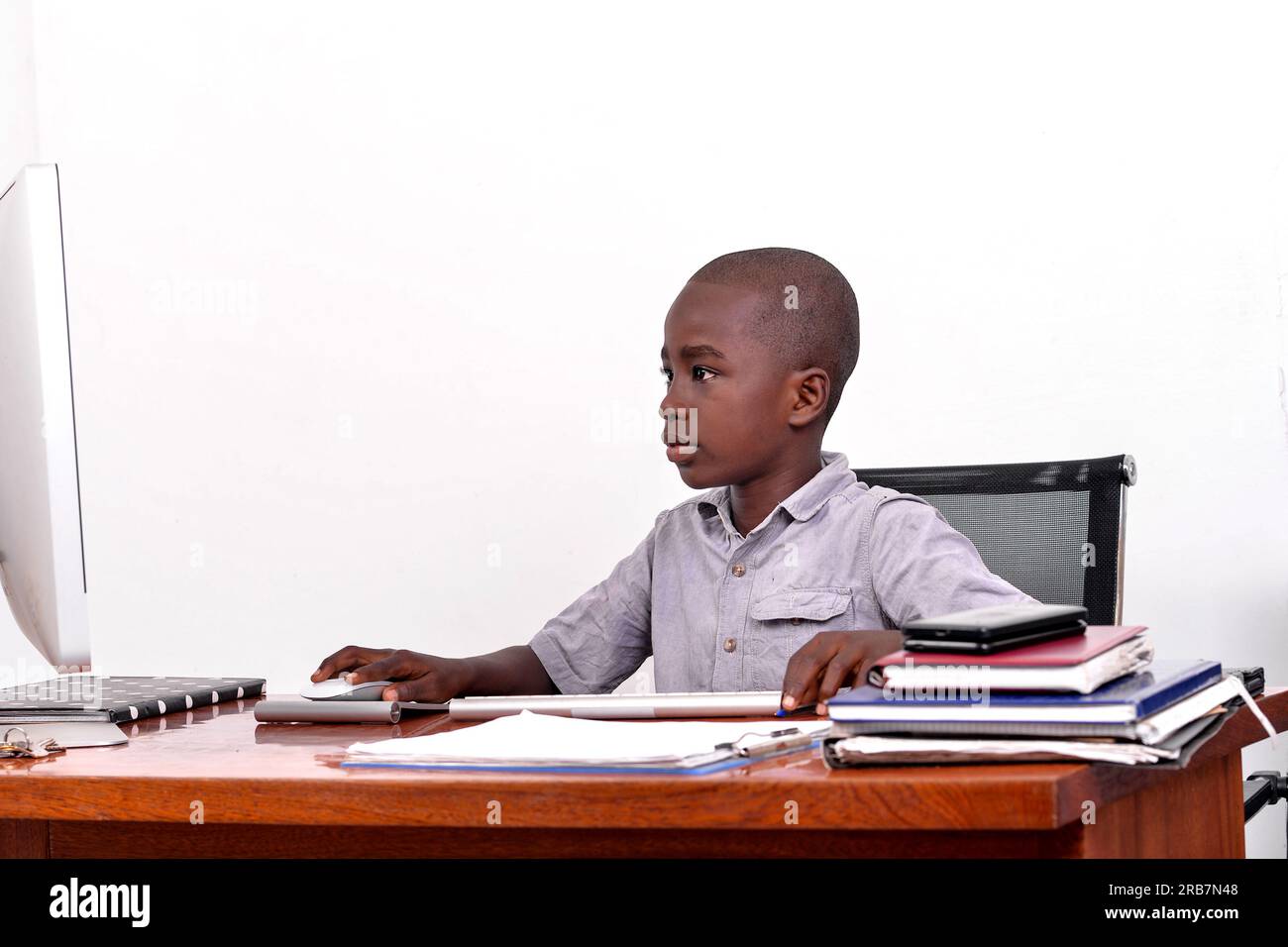 a young boy sitting in a desk looking at a computer screen Stock Photo ...