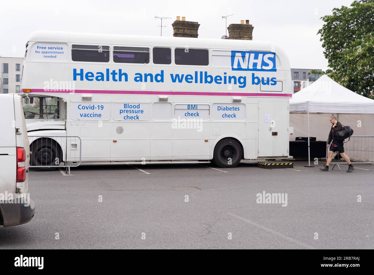 A man in shorts walks to NHS bus offering Health and Wellbeing services, Kent England UK Stock Photo