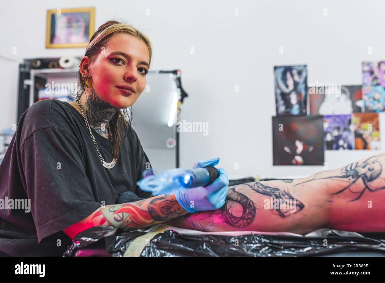 Confident female tattoo artist looking at camera while working on a new project. Tattooing studio interior. High quality photo Stock Photo