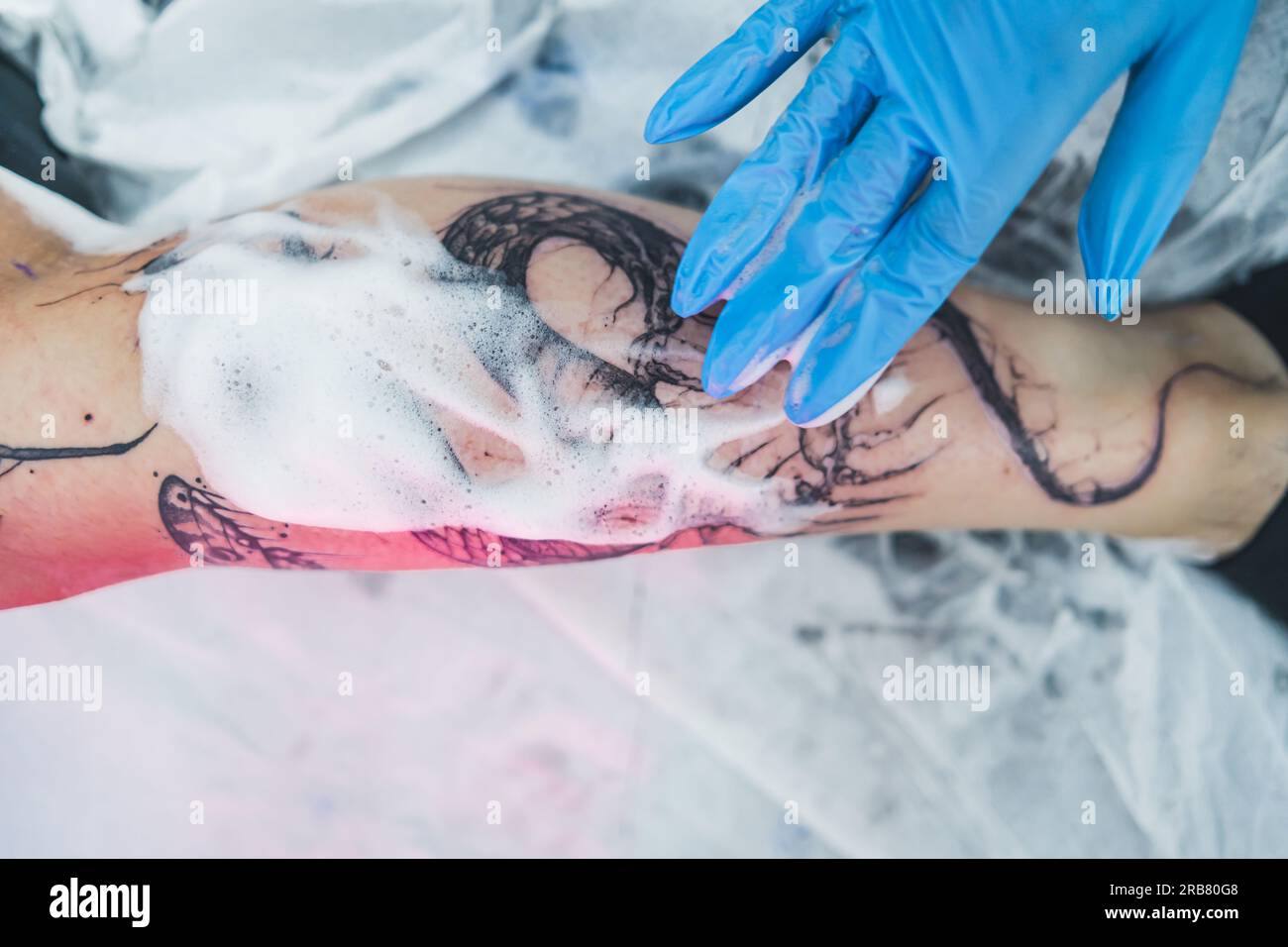 High angle shot fresh tattoo being cleaned with white foam. Cleansing process of a new tattoo. Professional tattoo studio. High quality photo Stock Photo