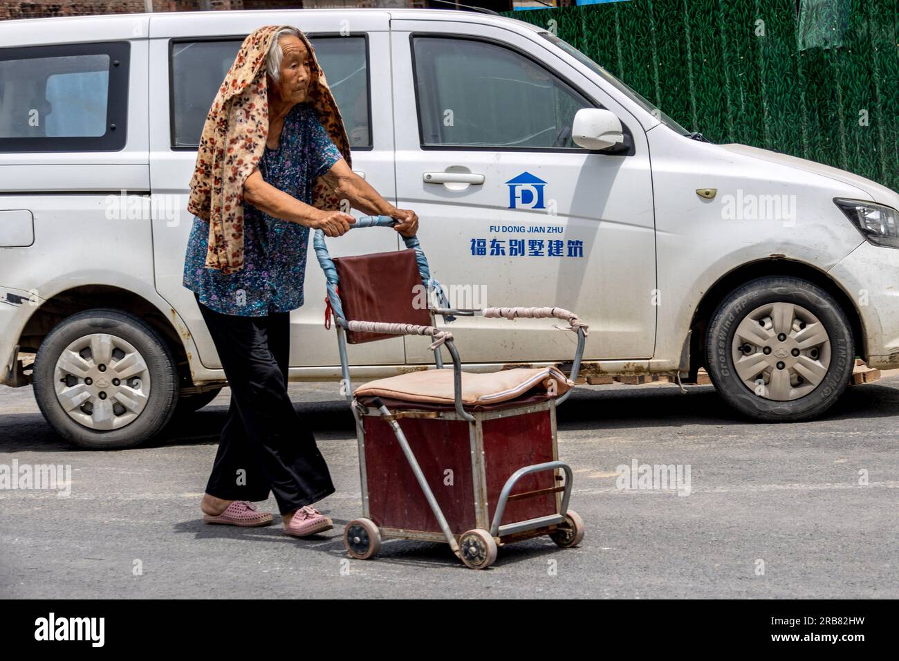 ANYANG, CHINA - JULY 8, 2023 - An elderly person    wearing protective clothing walks on a street in a temperature of 40 degrees Celsius in Hua County Stock Photo