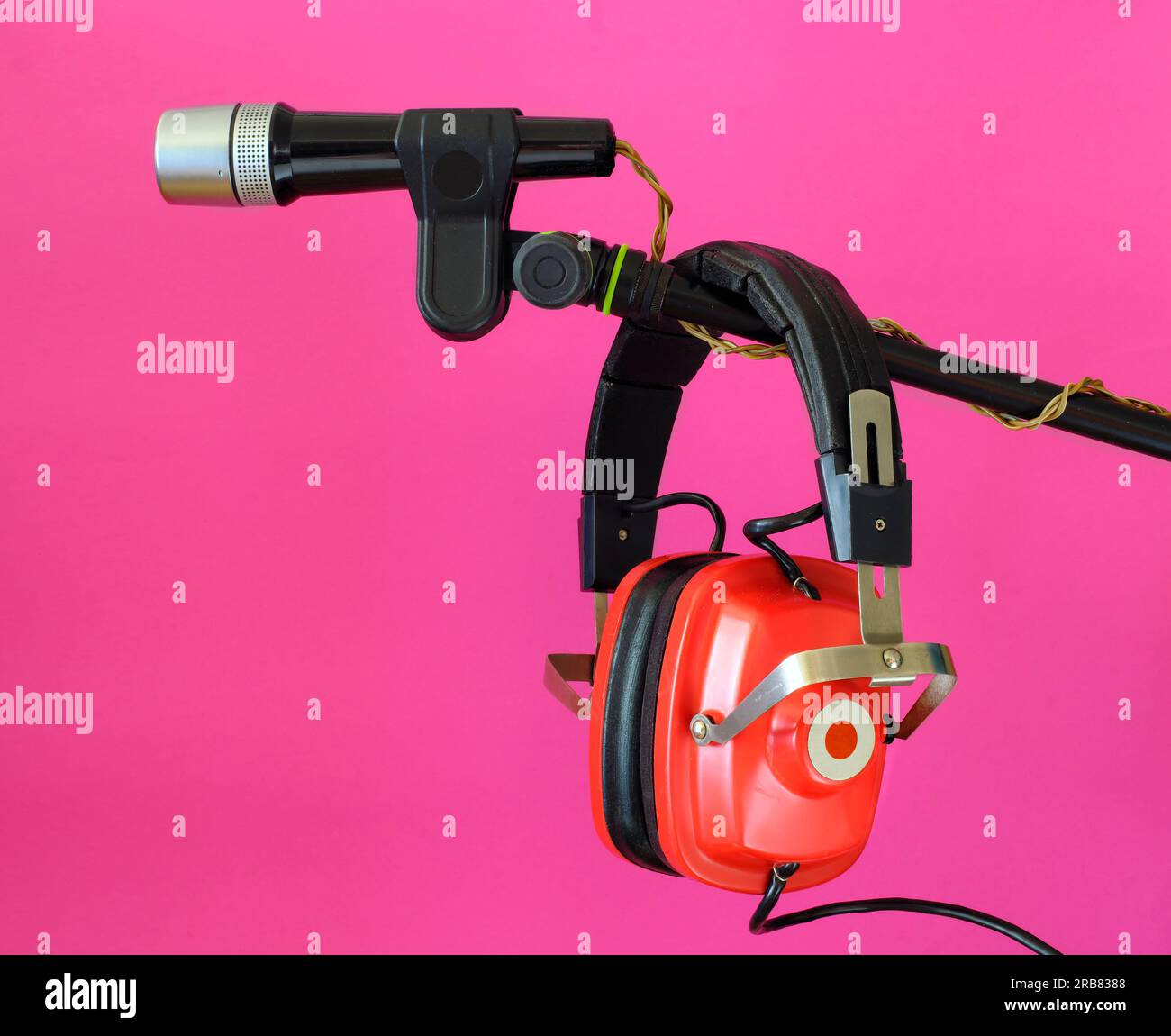 Vintage red headphone and old microphone on pink background, podcast,recording sound,vinatge audio gear concept. Free copy space. Stock Photo