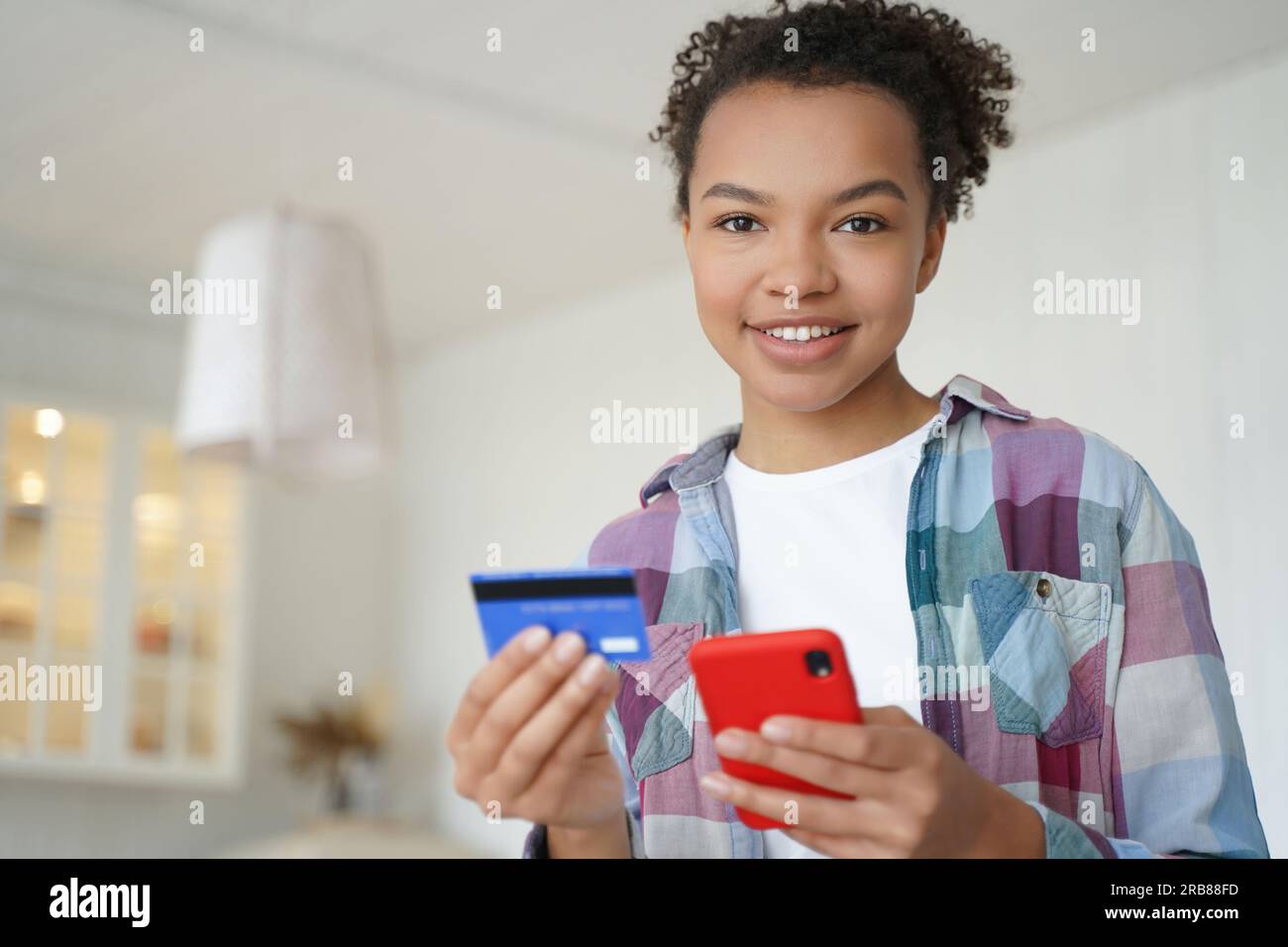 Happy biracial teen pays with credit card, smartphone. Using online