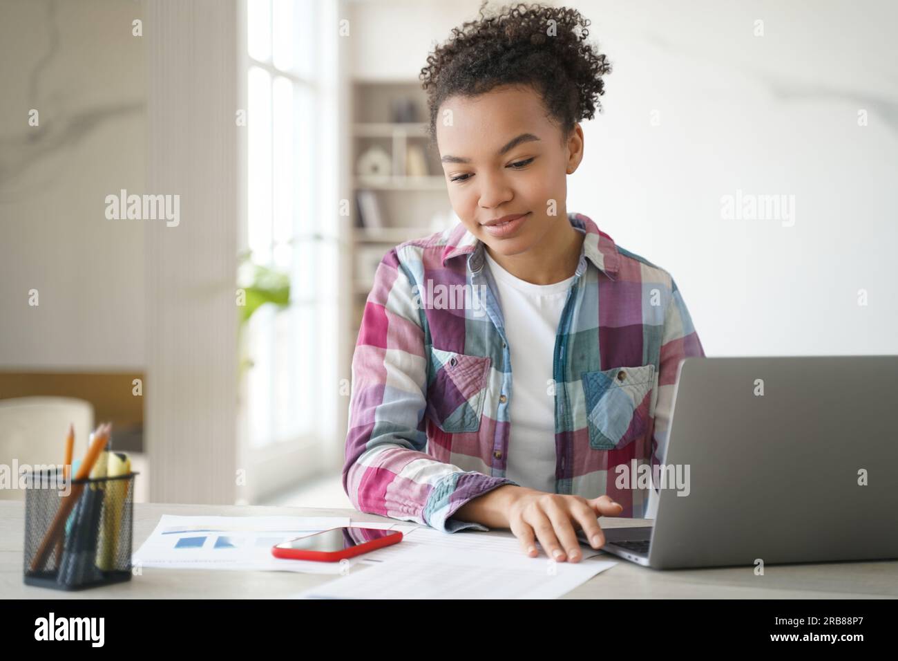 Distracted biracial student: laptop learning interrupted by phone ...