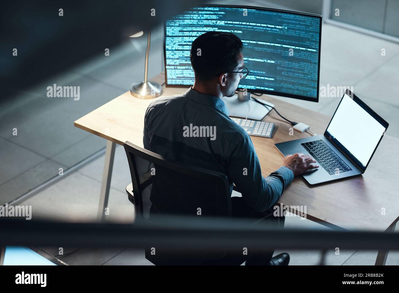 Man, programmer and coding at night on laptop mockup screen for networking, malware or software at the office. Male person, coder or developer working Stock Photo
