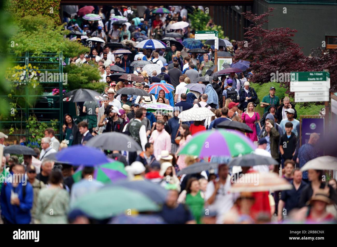 Spectators take shelter during a rain delay on day six of the 2023 Wimbledon Championships at