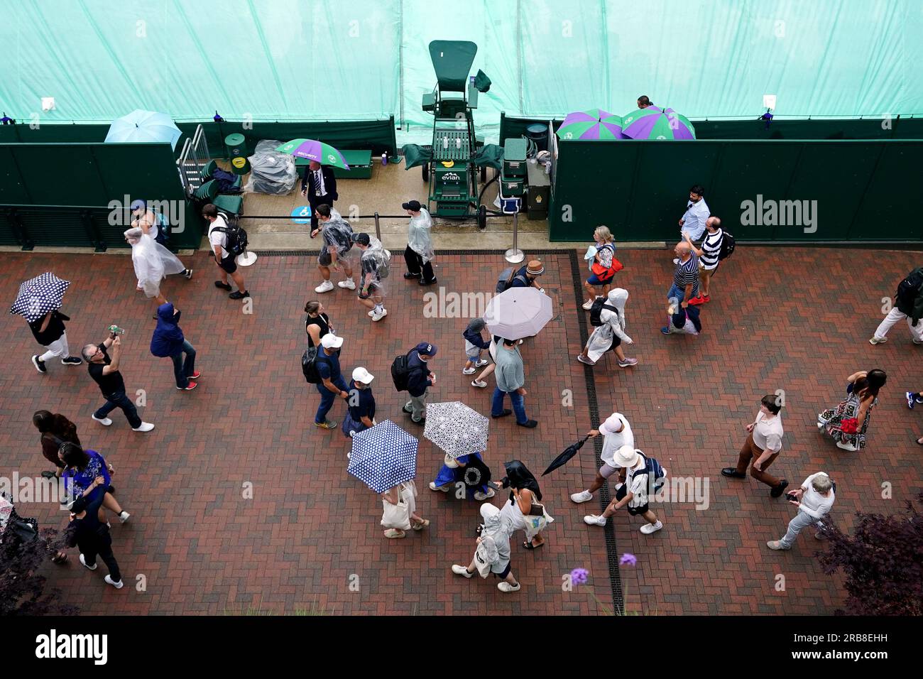 Spectators take shelter during a rain delay on day six of the 2023 Wimbledon Championships at