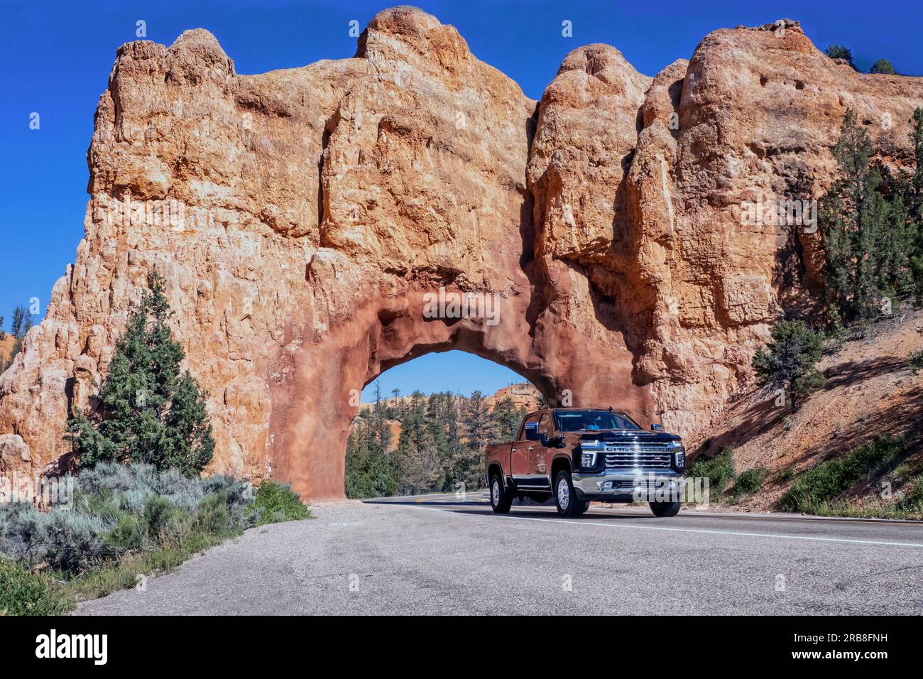 Chevrolet Pickup truck driving through arch on Red Canyon HWY 12 Utah Stock Photo