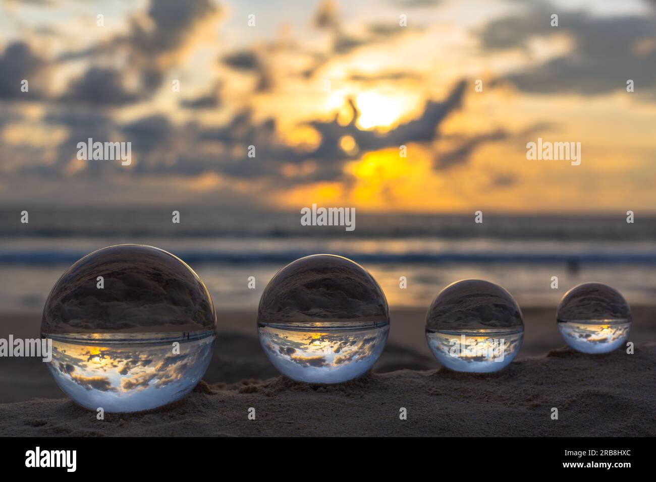 The 4 glass balls are arranged from large to small placed on the beach at  sunrise. To see the sea upside down in a glass ball. A image for a unique a  Stock Photo - Alamy