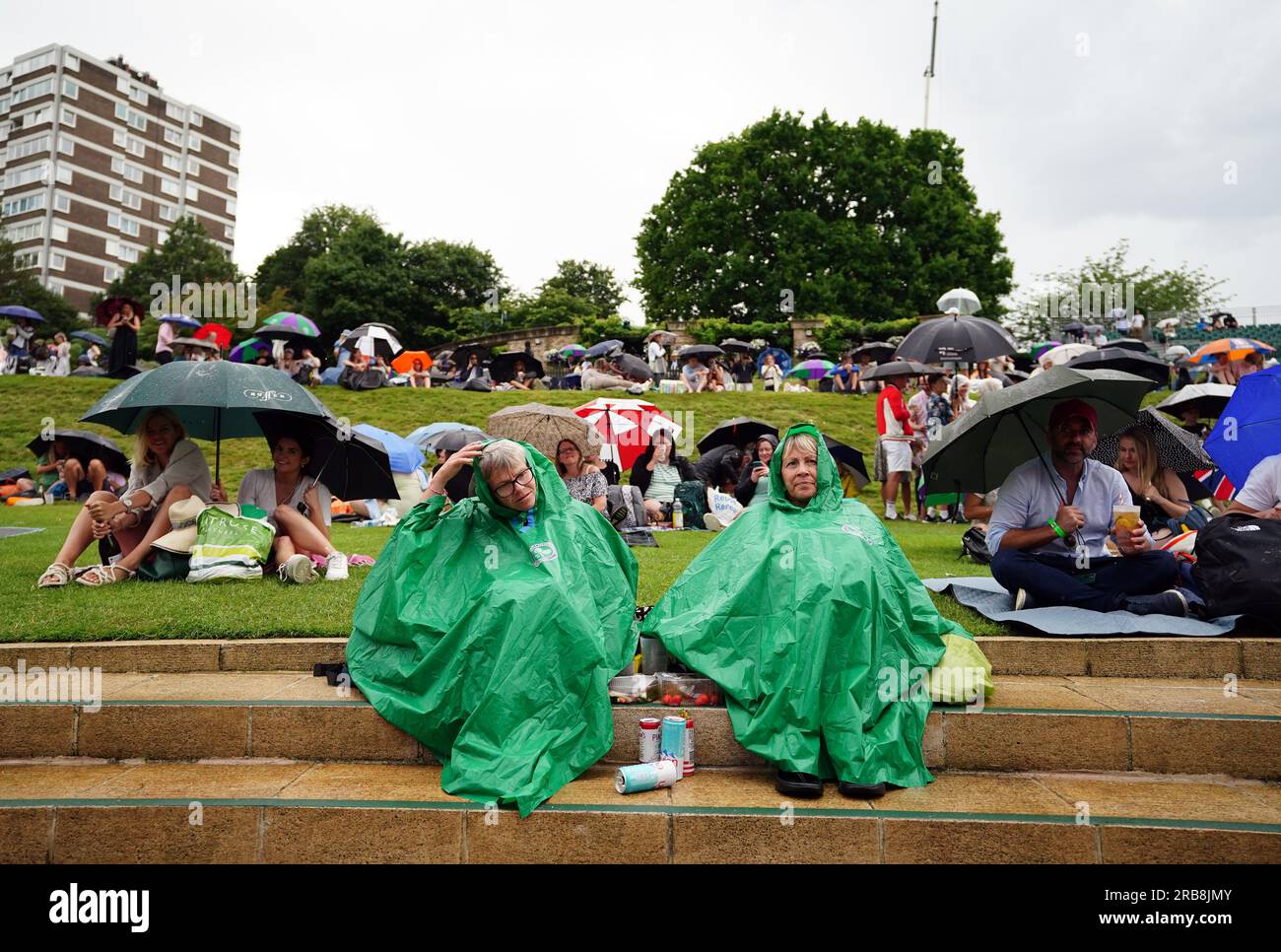 Spectators take shelter during a rain delay on day six