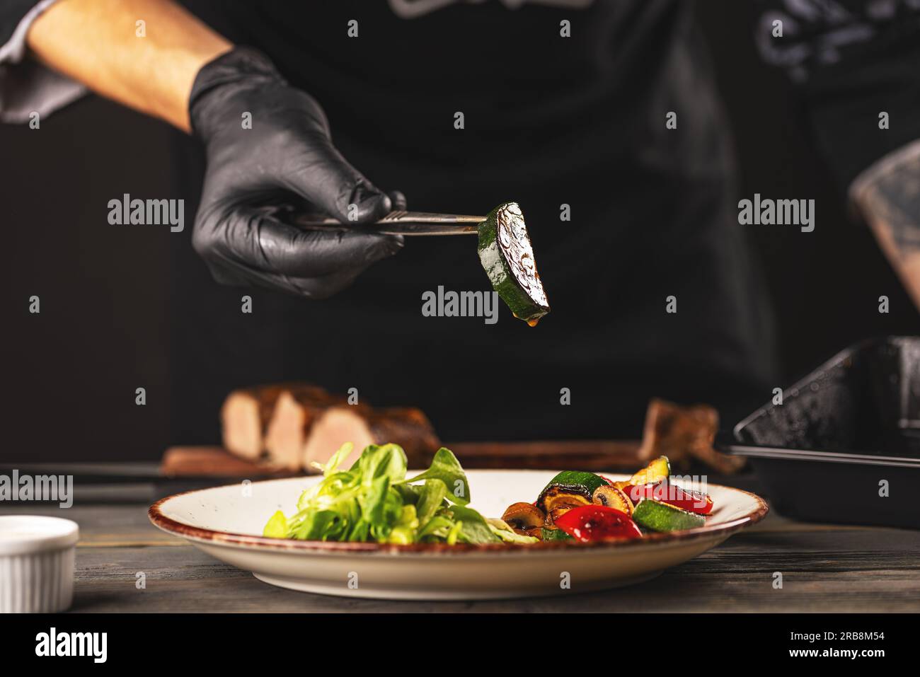 Close-up of chef putting fried zucchini on the plate Stock Photo