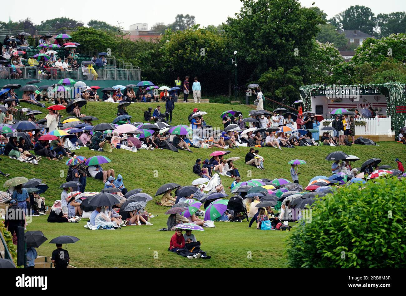 Spectators take shelter during a rain delay on day six