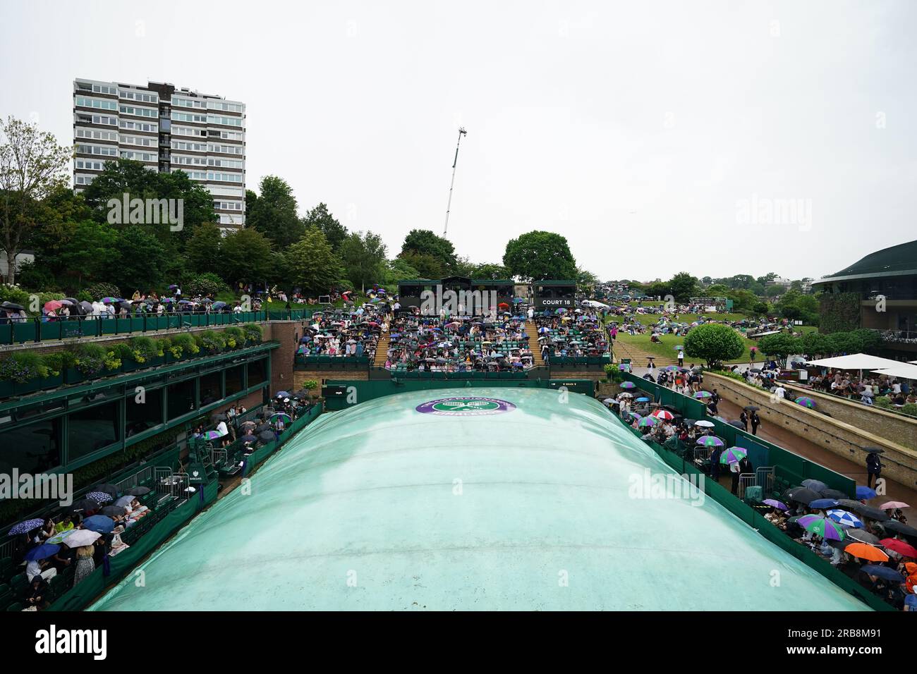 Spectators take shelter during a rain delay on day six of the 2023 Wimbledon Championships at