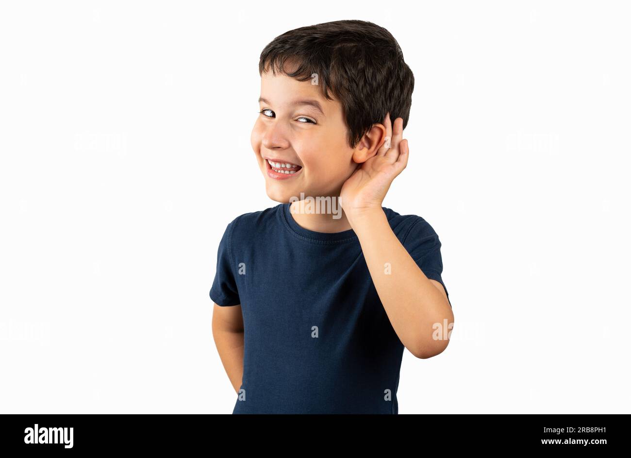 Young boy over isolated background smiling with hand over ear listening an hearing to rumor or gossip. Deafness concept. Stock Photo
