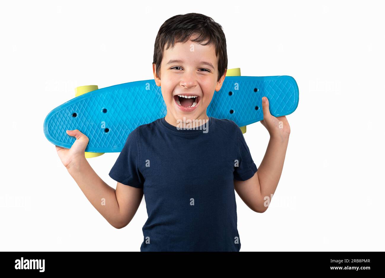 Happy boy laughing and holding bright blue skateboard over vibrant white background isolated Stock Photo