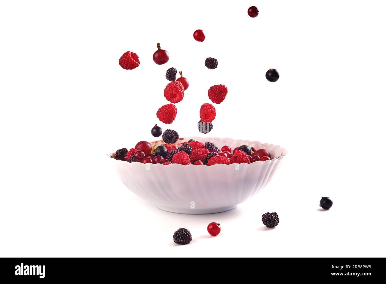 various berries, raspberry, currant on a plate isolate on white, berries are falling Stock Photo
