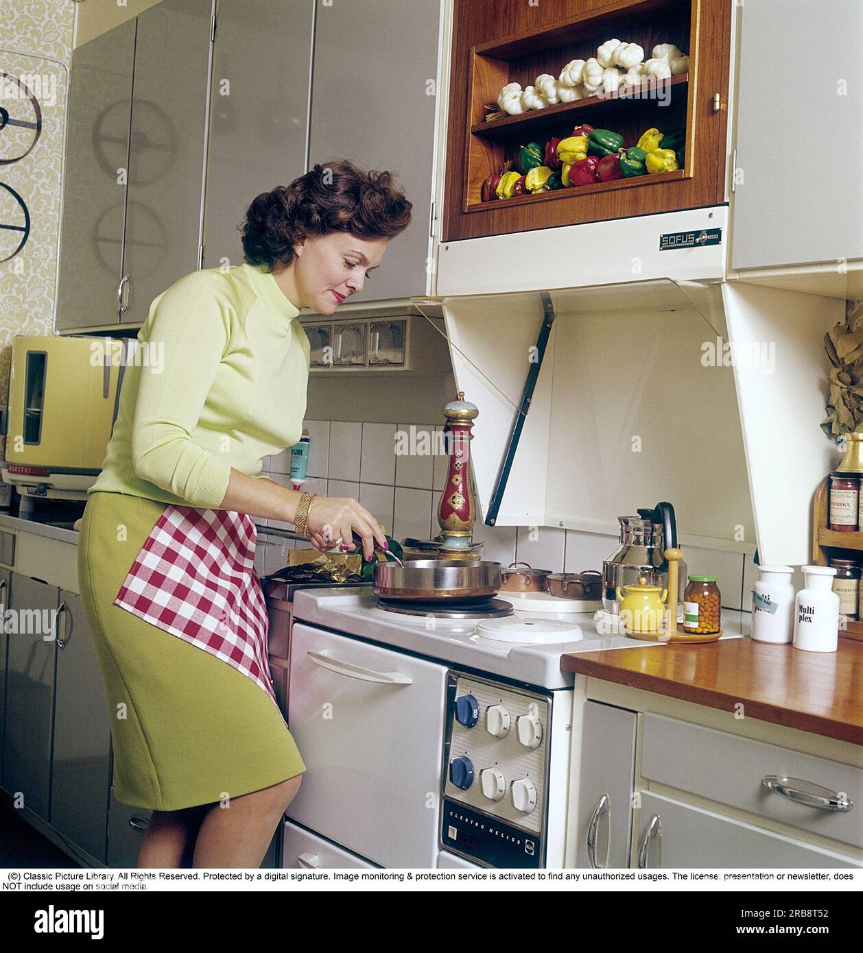 Haide Göransson (1928-2008)  Swedish actor and fashion model.  Here at home, in the kitchen where she stands by the stove and cooks, in the corner is a round countertop dishwasher from the brand electrolux, also called the round can, something that is easy to understand as the dishwasher has the odd round shape. Sweden 1968. Kristoffersson Stock Photo