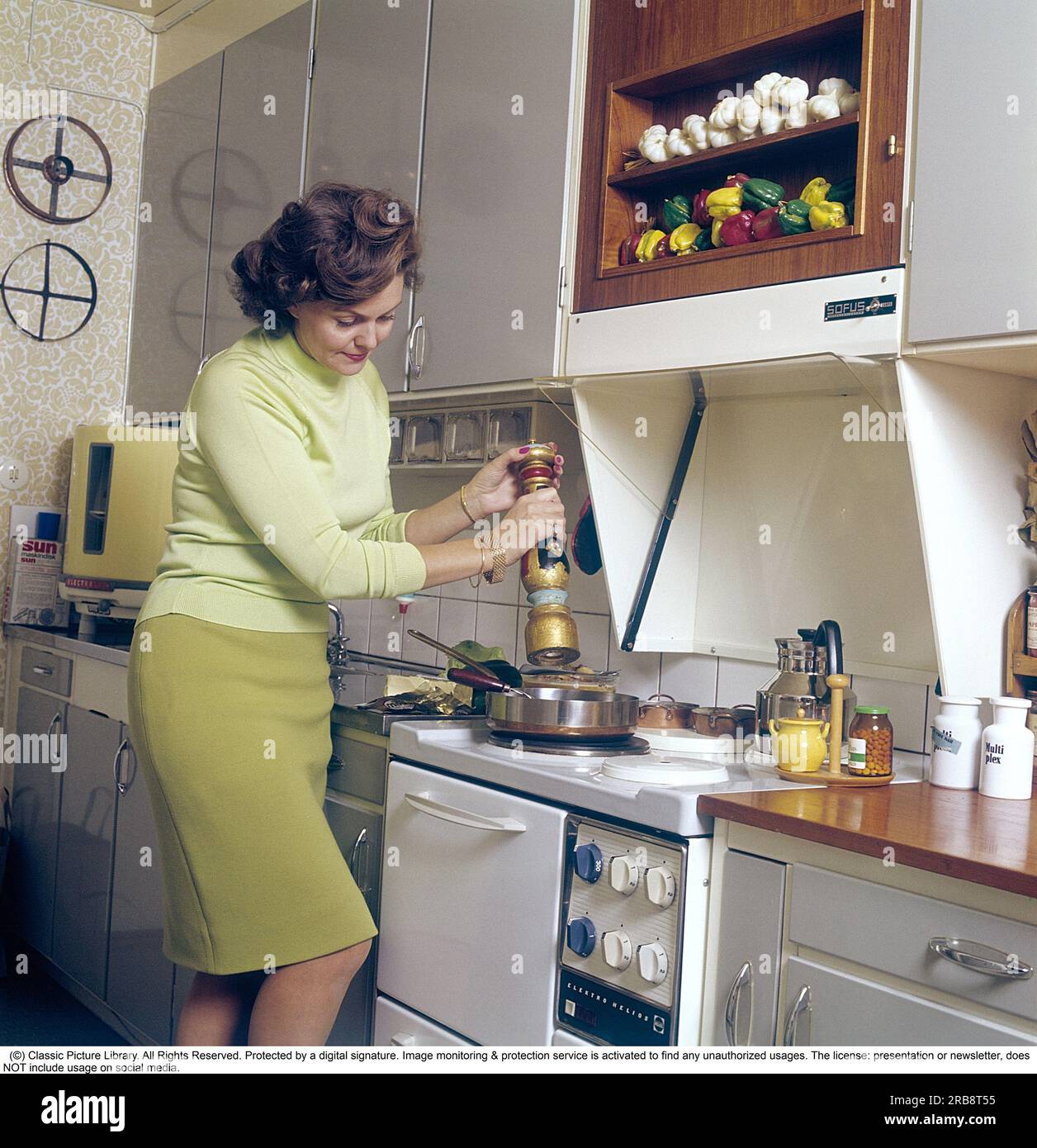 Haide Göransson (1928-2008)  Swedish actor and fashion model.  Here at home, in the kitchen where she stands by the stove and cooks, in the corner is a round countertop dishwasher from the brand electrolux, also called the round can, something that is easy to understand as the dishwasher has the odd round shape. Sweden 1968. Kristoffersson Stock Photo