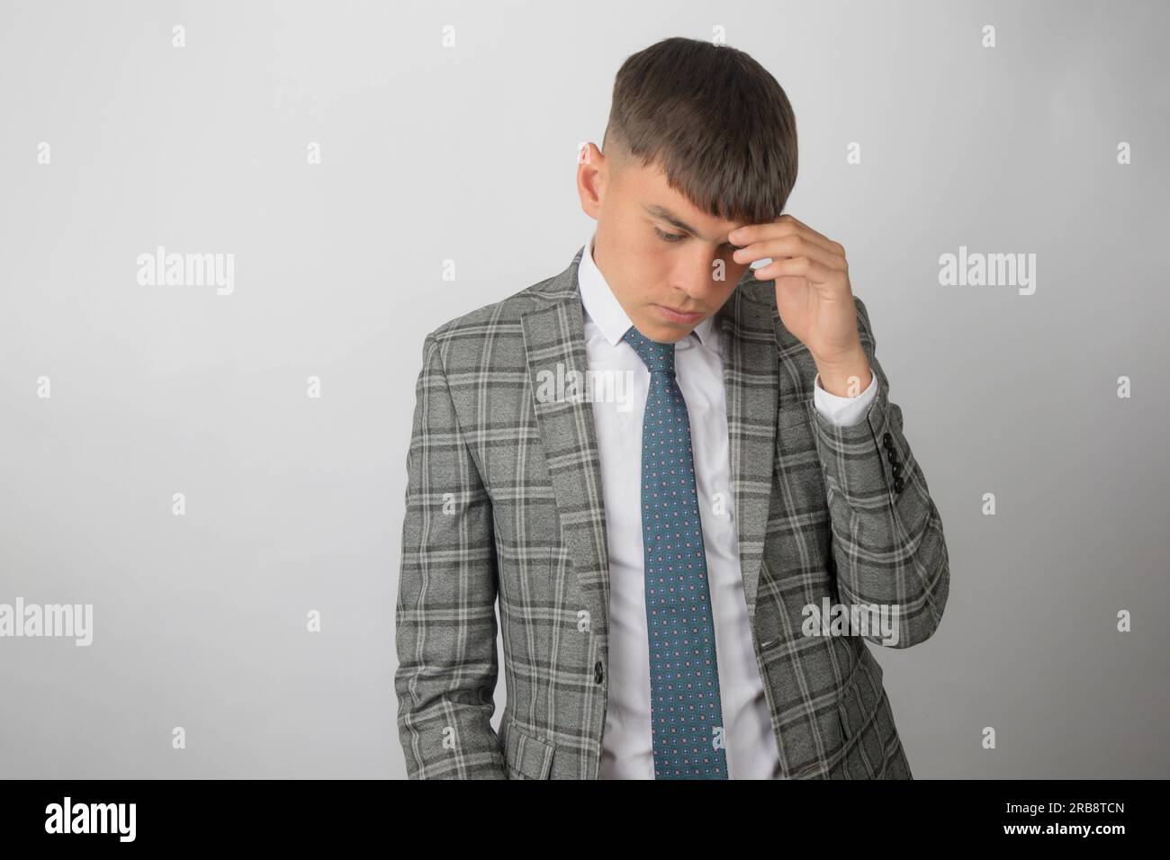 Young entrepreneur wearing a suit and tie rubbing his head with stress Stock Photo