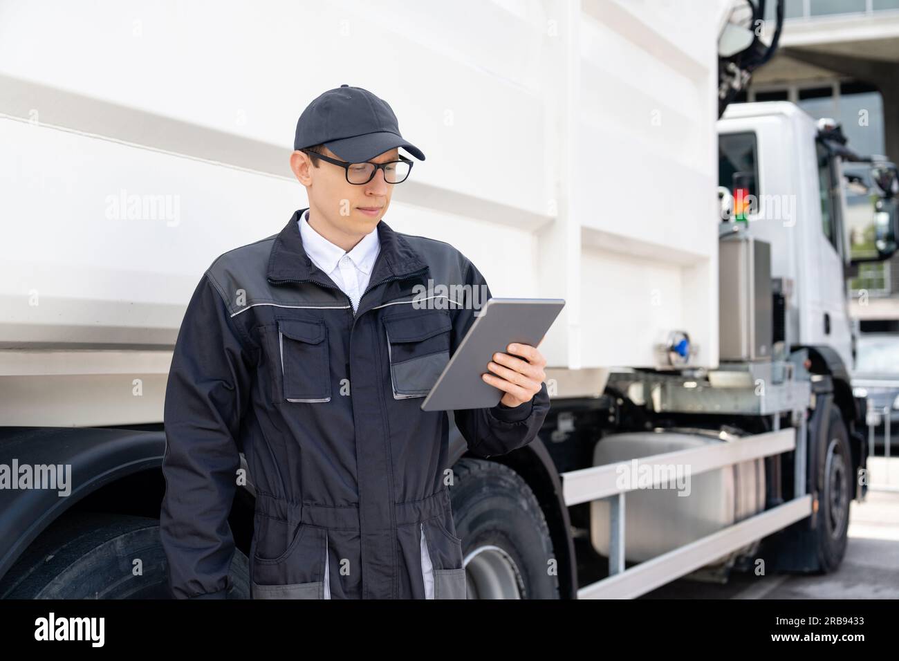 Manager with a digital tablet next to garbage truck. Stock Photo