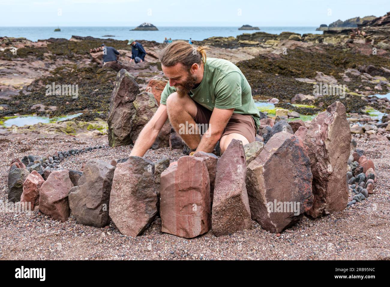 Dunbar, East Lothian, Scotland, UK, 8th July 2023. European Stone Stacking Championship: the final days of the European Land Art Festival with land artists creating land art. Pictured: Land artist Jon Foreman creates a henge-like sculpture. Credit: Sally Anderson/Alamy Live News Stock Photo