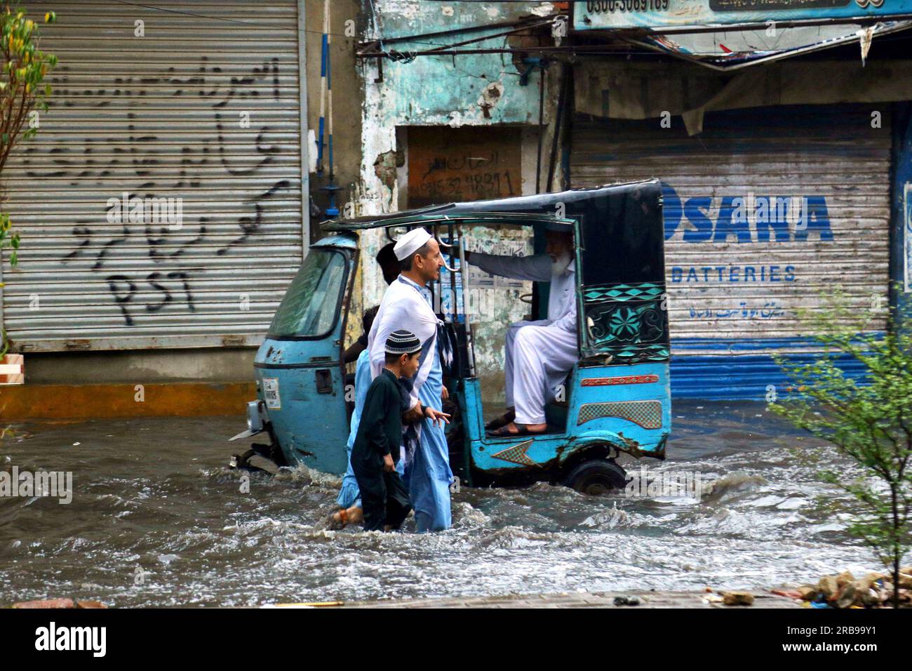 Hyderabad. 7th July, 2023. Commuters wade trough a flooded road after ...