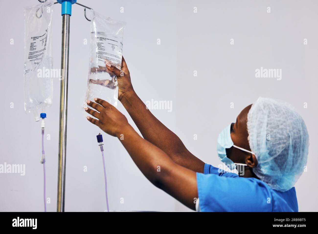 Hospital, nurse with face mask and black woman with iv drip medicine, fluid infusion or liquid injection bag. Nursing, doctor or surgeon monitoring Stock Photo