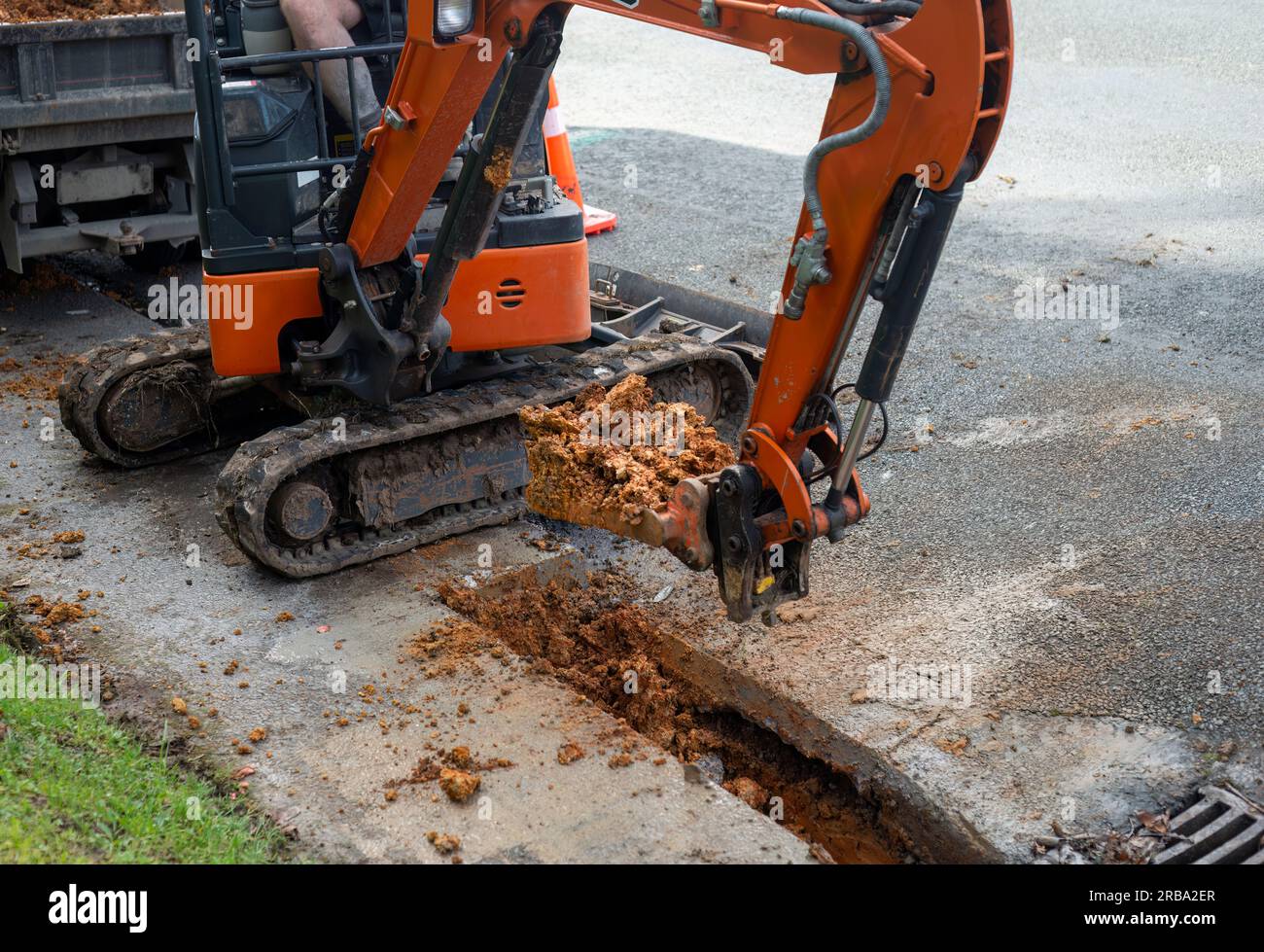 Excavator digging up dirt between cut concrete pavement to repair