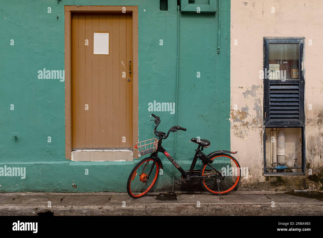 Kampong Glam, Singapore - December 19, 2022: A child bicycle against a green painted wall with no people Stock Photo