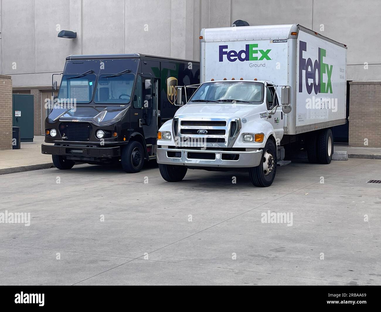 Buford, GA / USA - May 30, 2023:  A UPS truck is parked beside a FedEx truck at the loading dock of a shopping mall, on May 30, 2023 in Buford, GA. Stock Photo