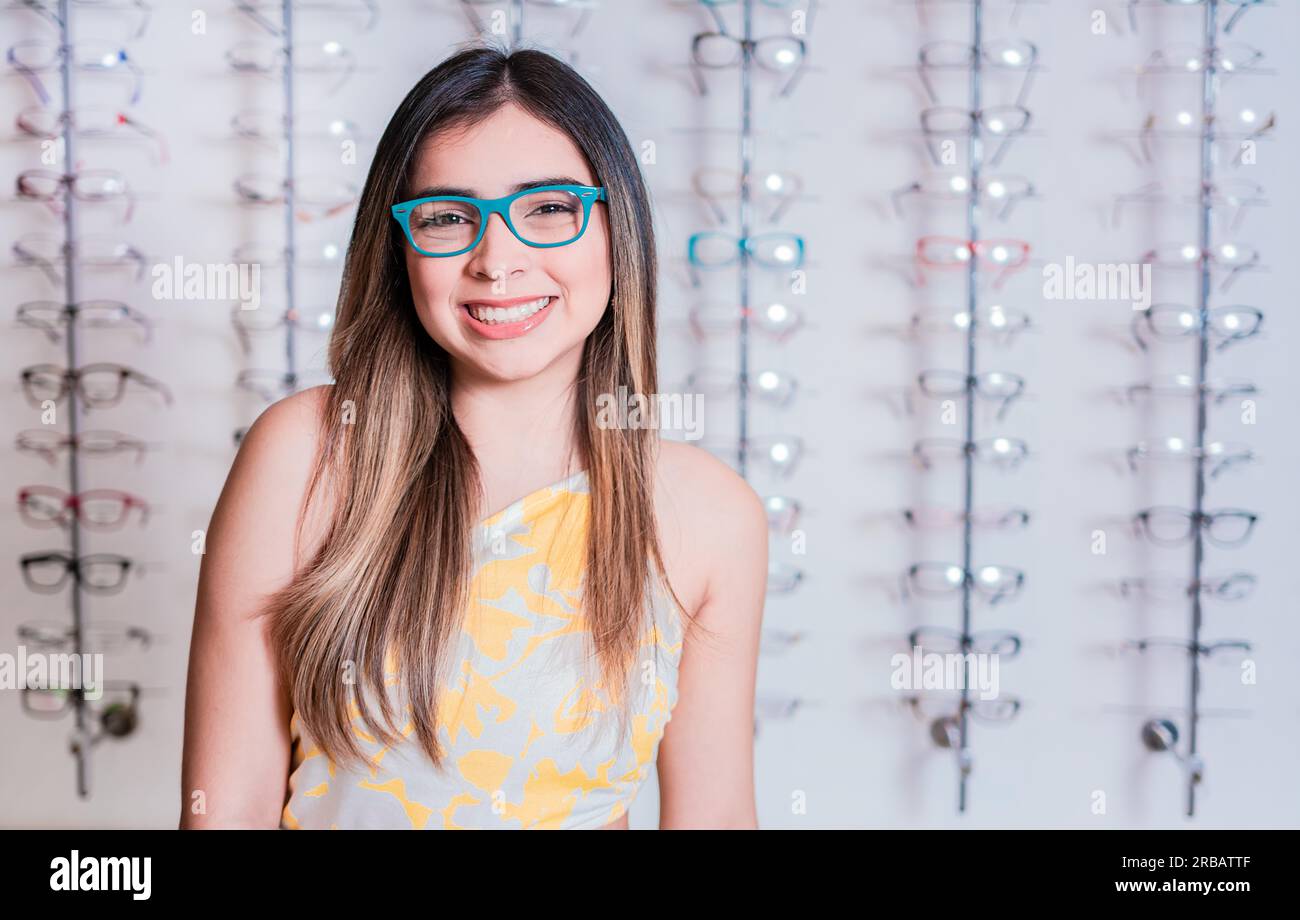 Portrait of happy girl in glasses in an eyeglasses store. Smiling happy girl in eyeglasses with store eyeglasses background Stock Photo