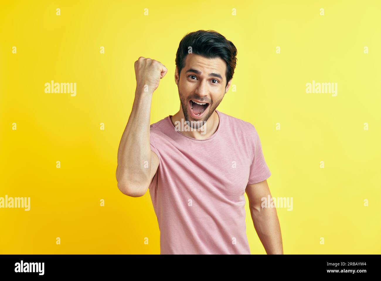 Happy man celebrating his success with winner gesture on yellow background. victory, triumph and emotions concept Stock Photo