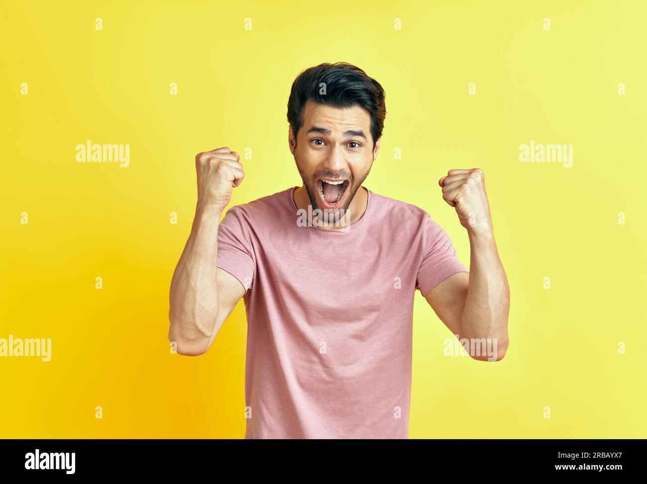 Happy man celebrating his success with winner gesture on yellow background. victory, triumph and emotions concept Stock Photo