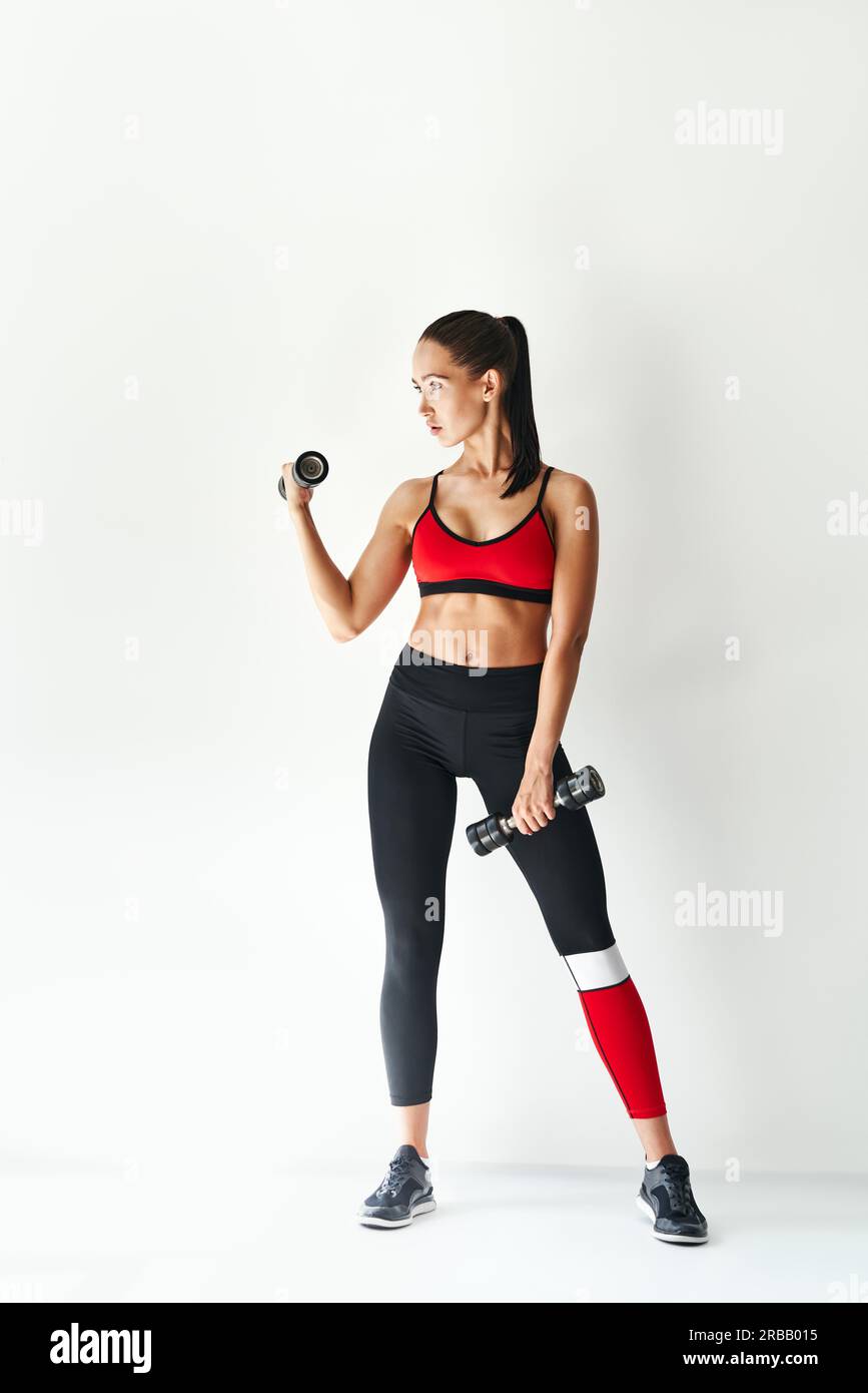 Sporty woman in sportswear doing exercise with dumbbells on white background. Strength and motivation concept. Full lenght portrait Stock Photo