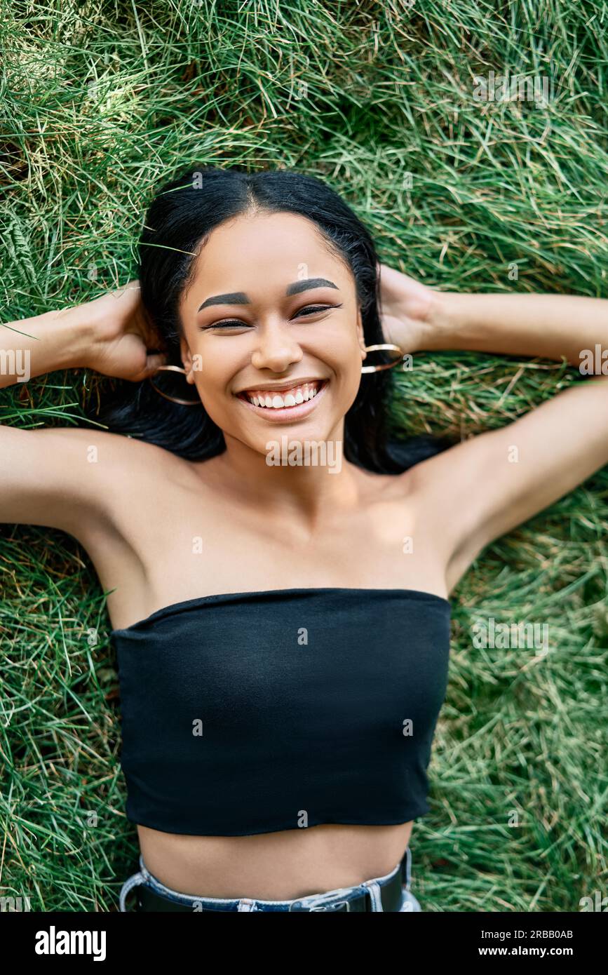 Top view portrait of pretty happy afro american woman relaxing on grass in park. Rest, female beauty concept Stock Photo