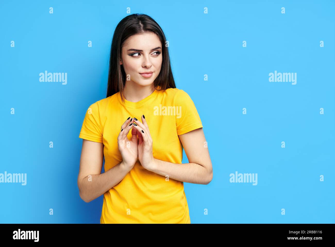 Sly pretty woman has interesting plan in mind, looks aside on blue background. cunning expression, thoughtful dreamy look Stock Photo