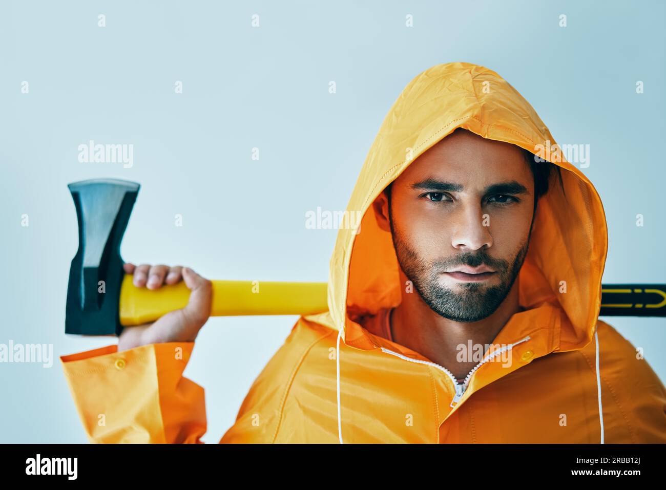 Portrait of brutal handsome man in bright raincoat holding big axe. lumberjack, fisherman with ax Stock Photo