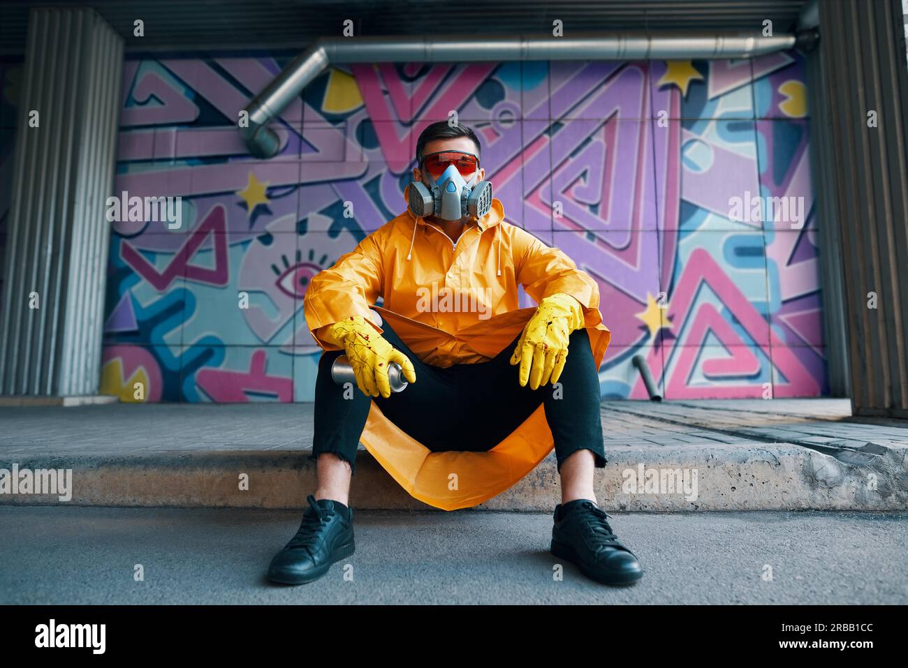 Graffiti painter rest near the wall with his paintings looking to