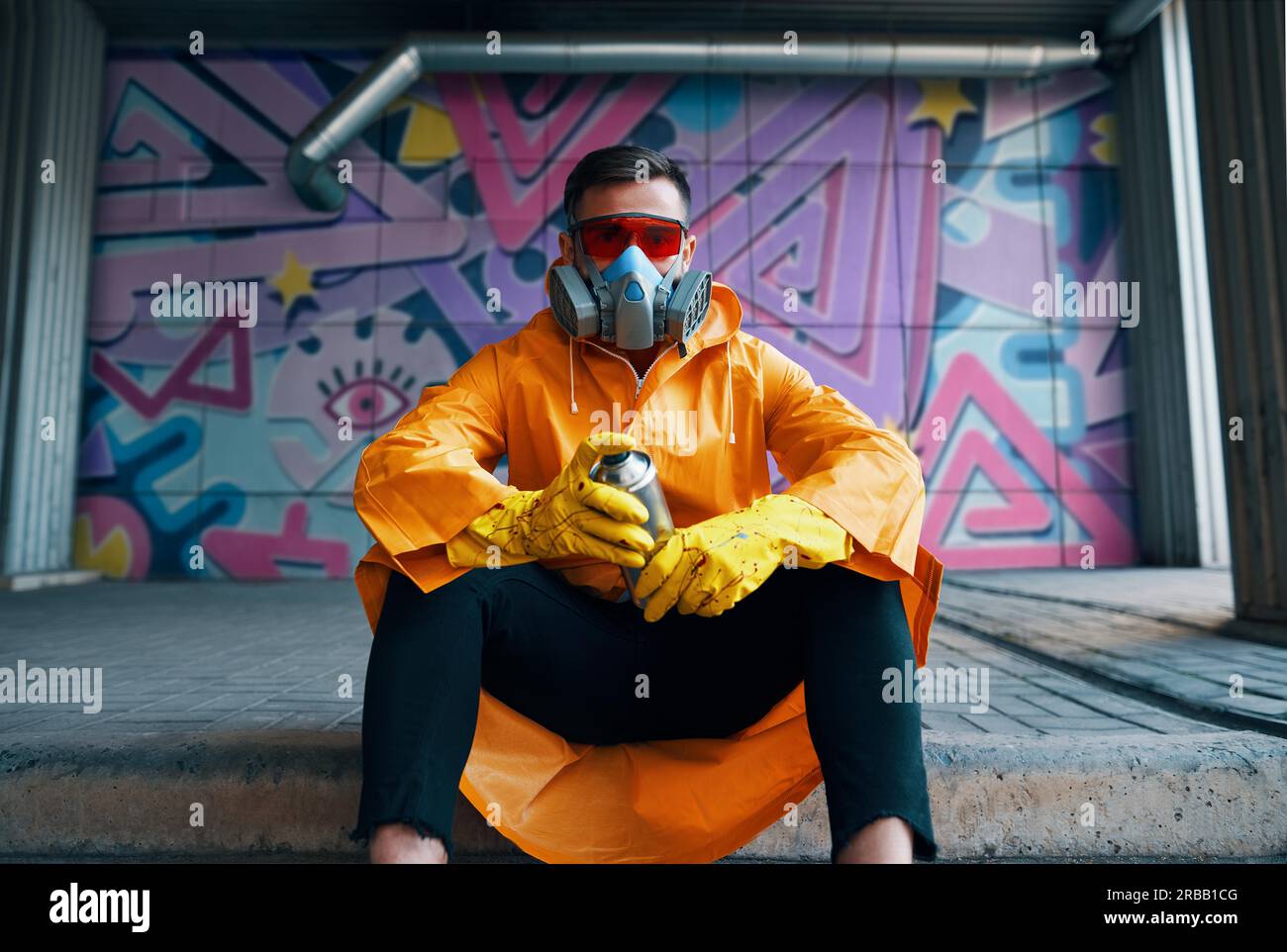 Graffiti painter rest near the wall with his paintings looking to