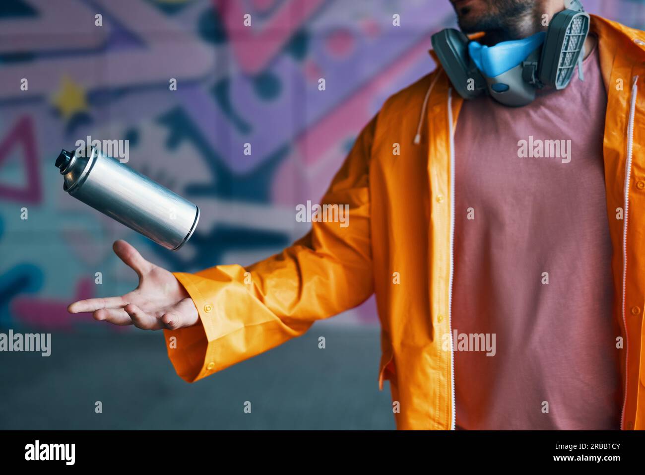 Graffiti artist throw his spray paint can against colorful graffiti on