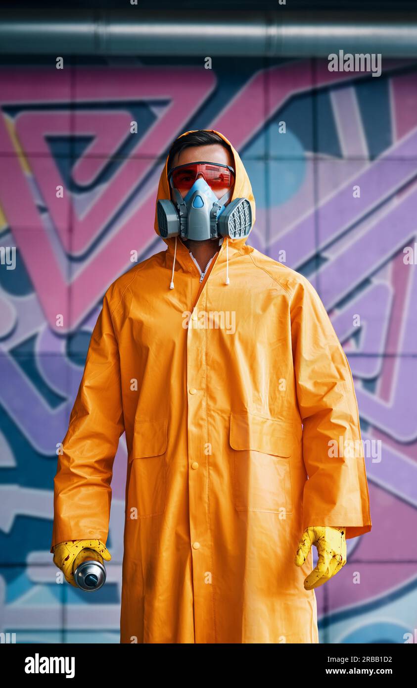 Graffiti painter in respirator mask standing near the wall with his
